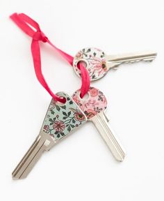 two keys are attached to a red ribbon with floral designs on them, and one is shaped like a heart