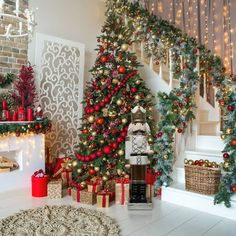 christmas trees decorated with red, gold and green ornaments in front of a staircase case