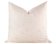 a pink pillow with white flowers on the front and back, sitting on a white surface