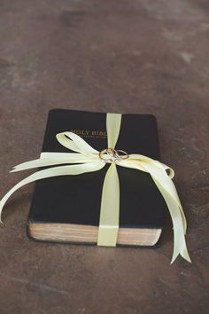 a black book with a yellow ribbon tied around the front cover and ring on top