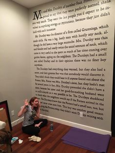 a woman sitting on the floor in front of a wall with words written on it