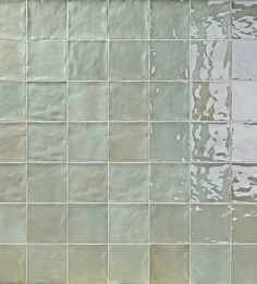 a white tiled wall with water running down it