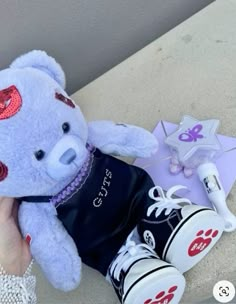 a white teddy bear sitting on top of a table next to a pair of shoes