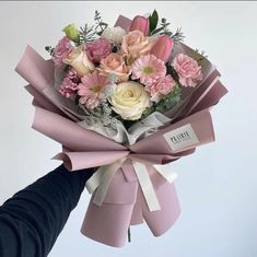 a bouquet of pink and white flowers is being held by a person's hand