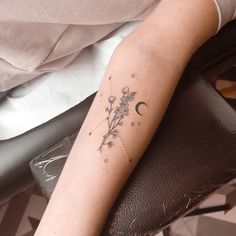 a woman's arm with a flower and moon tattoo on the left side of her arm