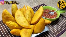 some fried food is on a table with a bowl of salsa and spoons next to it