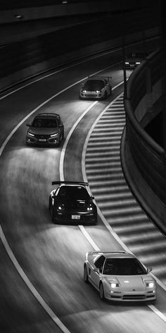 three cars are driving down the highway at night in black - and - white photo