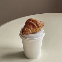 a croissant sitting on top of a white cup