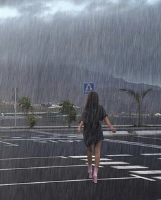 a woman walking across a parking lot in the rain