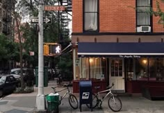 two bikes are parked in front of a restaurant on the street corner near a traffic light