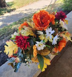 a bouquet of flowers sitting on top of a wooden bench