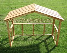 a wooden gazebo sitting on top of a lush green field