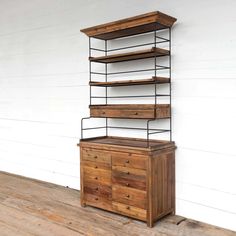 a wooden dresser with metal shelves and drawers on the top, against a white wall