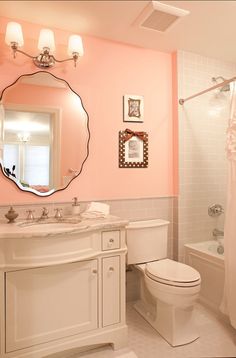 a bathroom with pink walls, white fixtures and a large mirror above the toilette