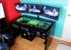 two computer monitors sitting next to each other on top of a wooden floor in front of a blue wall