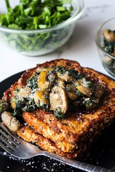 a piece of bread with spinach and mushrooms on it next to a bowl of greens