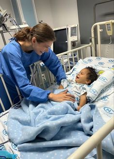 a female nurse tending to a baby in a hospital bed