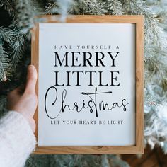 someone is holding up a christmas card in front of a tree with the words, have yourself a merry little christmas let your heart be light