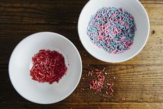 two white bowls filled with sprinkles on top of a wooden table next to each other