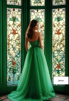 a woman standing in front of stained glass windows wearing a green gown with bow at the waist