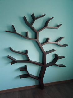 a metal tree sculpture sitting on top of a wooden floor next to a blue wall