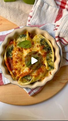 a casserole dish with spinach and cheese in it on a wooden platter