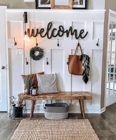 a wooden bench sitting in front of a white wall with a welcome sign on it