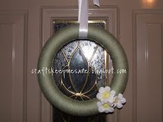 a green wreath with white flowers hanging from it's front door