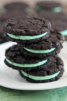 chocolate cookies with mint green frosting stacked on top of each other in a white plate