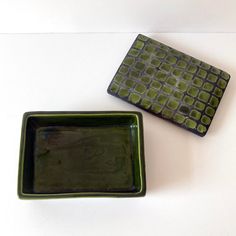 two green square dishes sitting on top of a white table next to eachother