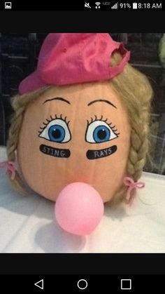 a stuffed doll with blue eyes and pink hat on it's head next to a balloon