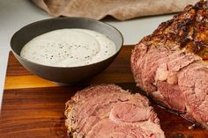 a piece of meat sitting on top of a cutting board next to a bowl of ranch dressing