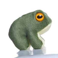 a green stuffed animal with an orange eye sitting on top of a white surface and looking at the camera