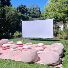 an outdoor movie is set up in the grass with bean bags and pillows on it