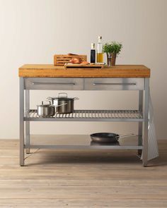 a kitchen island with pots and pans on the bottom shelf in front of it