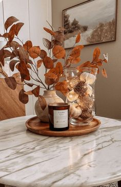 a marble table topped with a vase filled with leaves and a candle on top of it