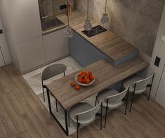 a modern kitchen with an island table surrounded by white chairs and gray countertops, along with a bowl of oranges on the dining room's edge