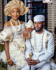 an african couple posing for a photo in their wedding attire and turban hats