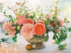 a vase filled with pink flowers sitting on top of a table next to two candles