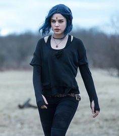 a woman with blue hair walking across a field