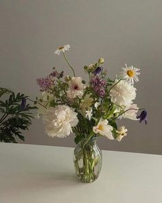 a vase filled with lots of white and purple flowers