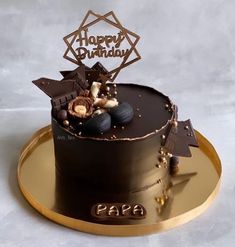 a chocolate birthday cake with wheels and decorations on it's top, sitting on a gold platter