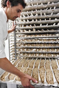 a man standing in front of a metal rack filled with cookies