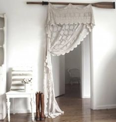 a white room with wooden floors and a window covered by a sheered drape