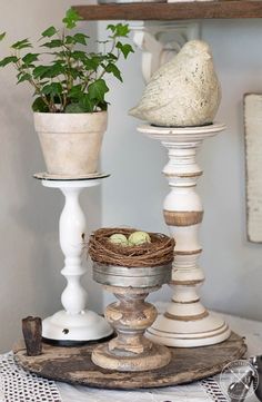 three white candlesticks with bird's nest in them on top of a table