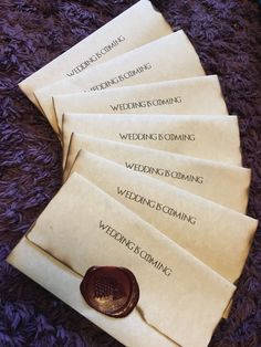 six wedding envelopes with wax stamp on them sitting on a purple carpeted surface