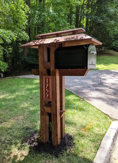 a mailbox in the middle of a grassy area with trees and grass around it