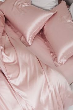 an unmade bed with pink sheets and pillows on top of it, next to a pillow case