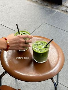 a person holding a drink on top of a table with two straws in it