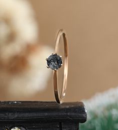 a close up of a ring with a stone in it on a table next to a flower